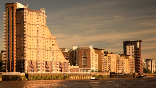 Riverside apartment buildings in London’s Docklands in warm evening sun, the Thames in front