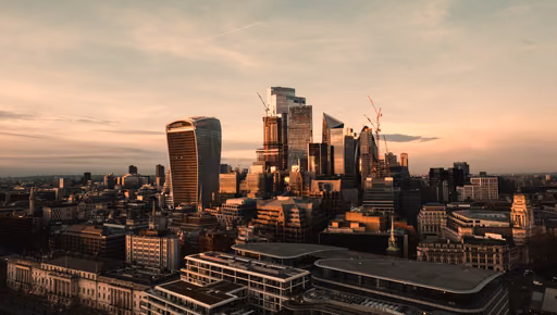 The City of London from above at sunset, its towers against a warm sky