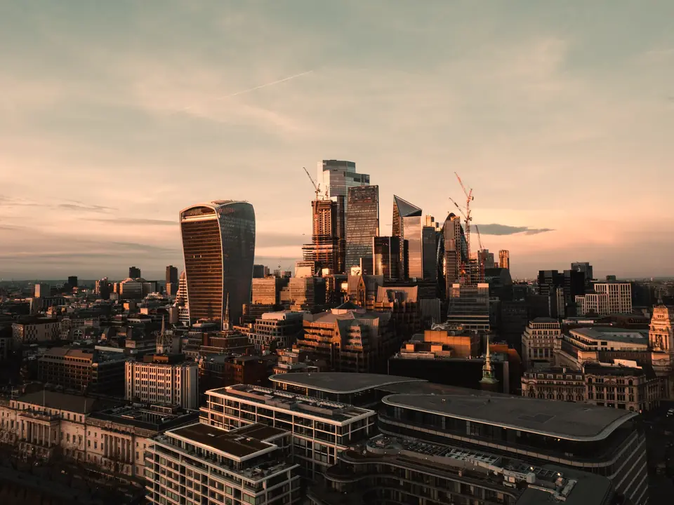 The City of London from above at sunset, its towers against a warm sky
